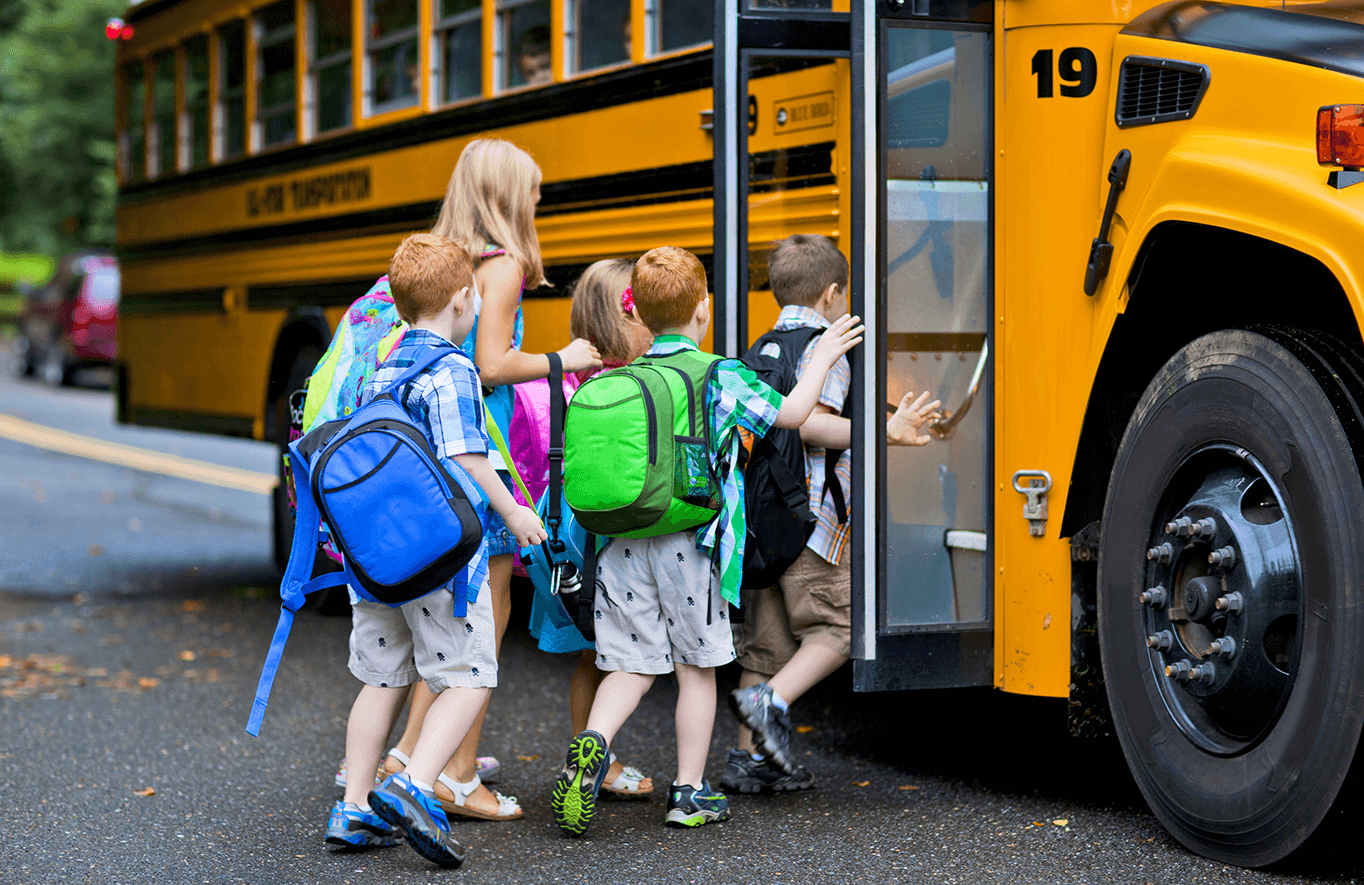 A group of young children getting on the school bus.